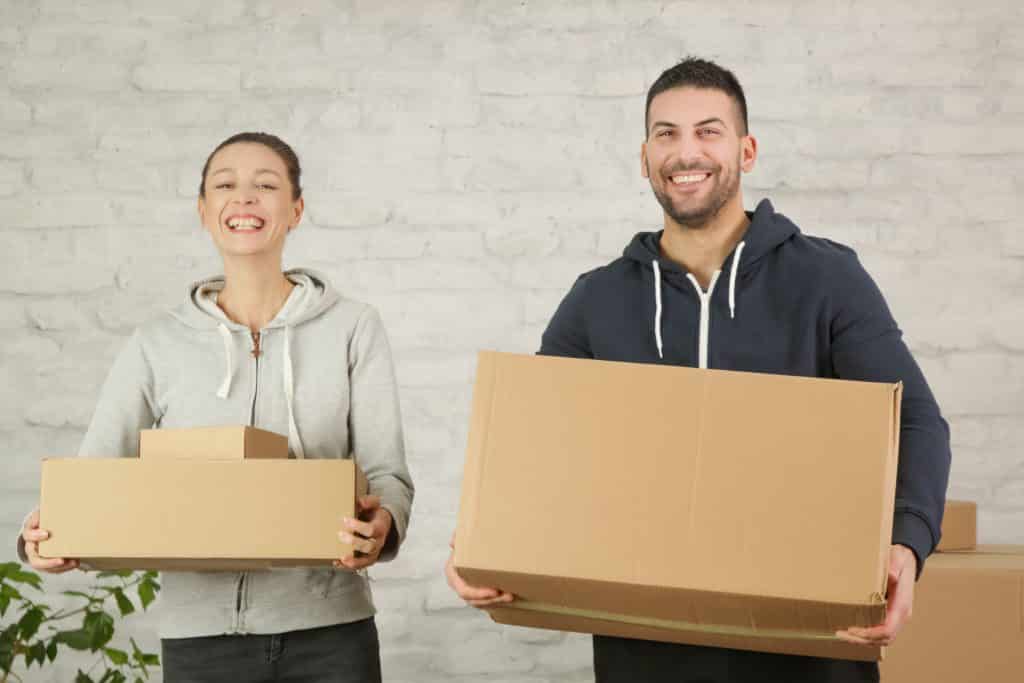 young,happy,couple,holding,cardboard,boxes,,moving,into,the,new