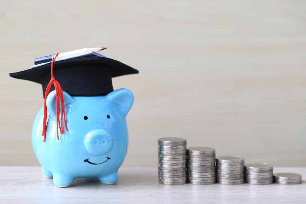 graduation,hat,on,blue,piggy,bank,with,stack,of,coins