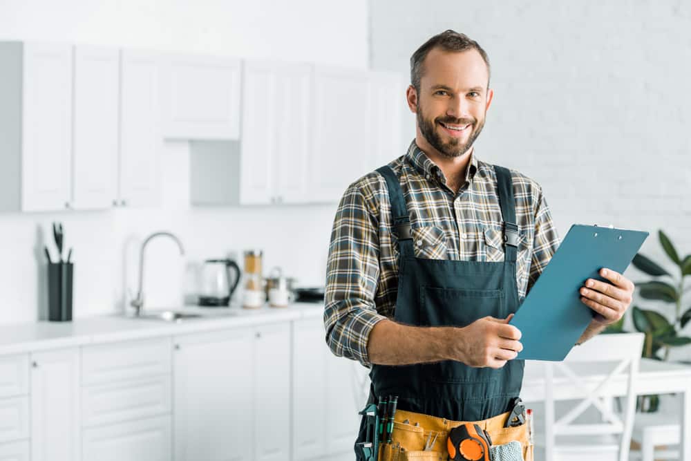 smiling,handsome,plumber,holding,clipboard,and,looking,at,camera,in