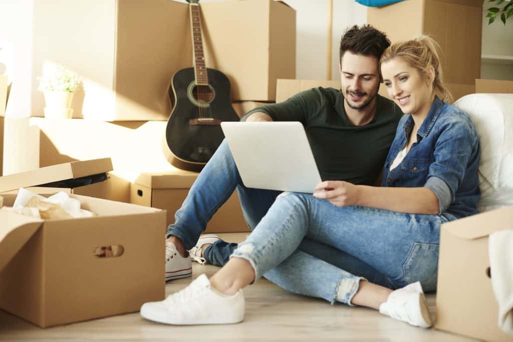 couple,with,laptop,around,cardboard,boxes