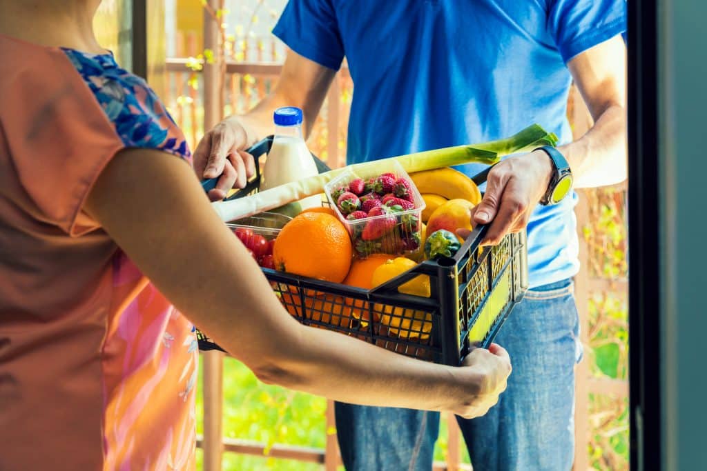 woman,accepting,groceries,box,from,delivery,man,at,home