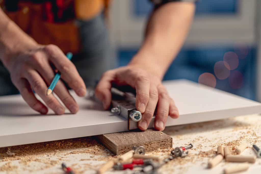 man,working,with,pencil,marking,holes,during,process,of,wooden