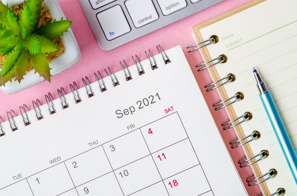 september,2021,calendar,with,note,book,on,pink,background.