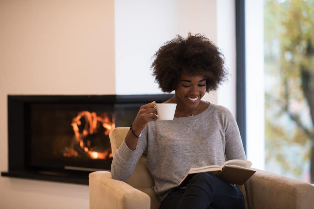 african,american,woman,drinking,cup,of,coffee,reading,book,at