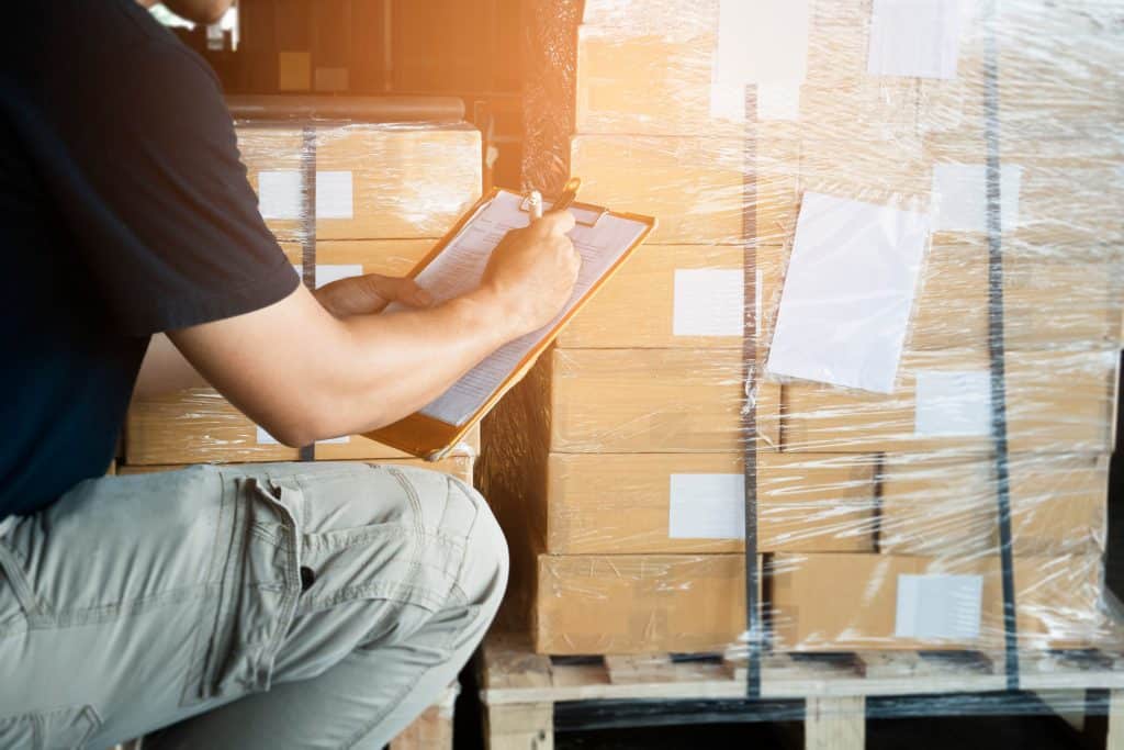 warehouse,worker,holding,clipboard,writing,on,checklist,for,delivering,shipment