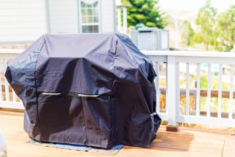 large,gas,grill,covered,with,black,cover,to,protect,from