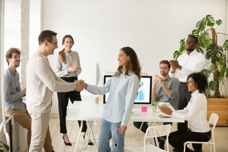 boss,shaking,hand,of,young,shy,woman,congratulating,successful,employee