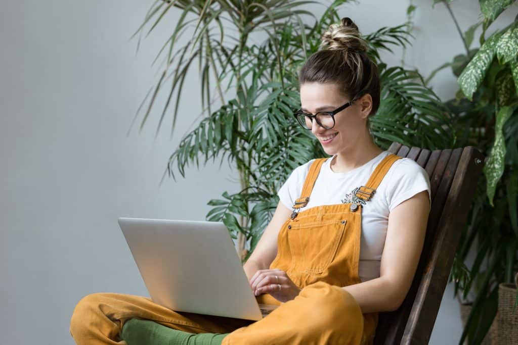 young,female,gardener,in,glasses,wearing,overalls,,sitting,on,wooden