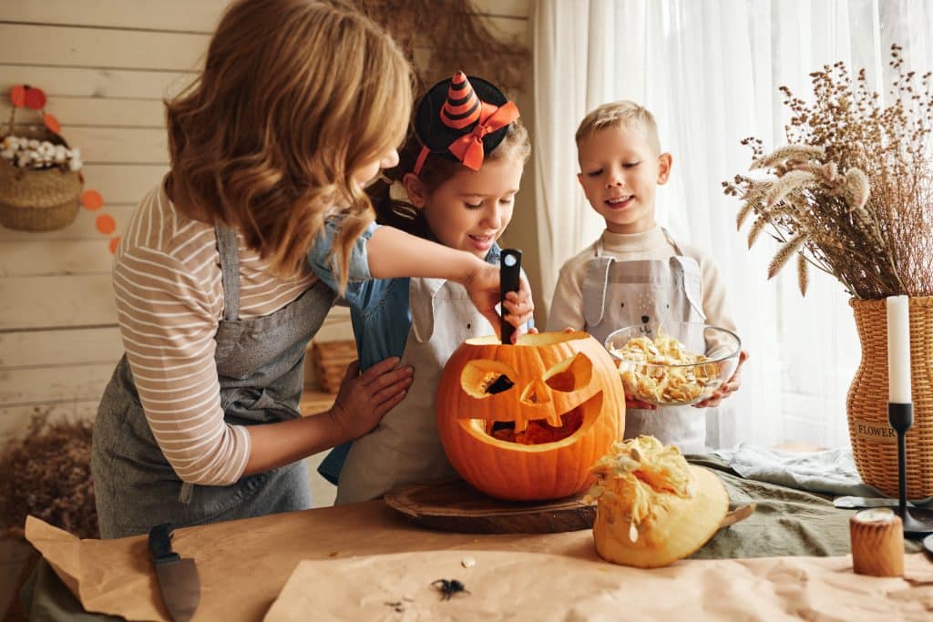 happy,family,mother,and,kids,carving,pumpkin,for,halloween,holiday